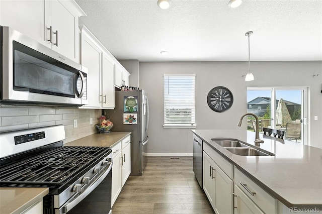 1670 Vantage Pkwy, Berthoud, CO 80513 - kitchen with appliances with stainless steel finishes, wood finished floors, an island with sink, backsplash, and white cabinets