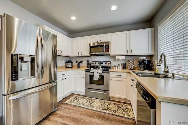 kitchen with sink, light hardwood / wood-style flooring, white cabinets, and appliances with stainless steel finishes