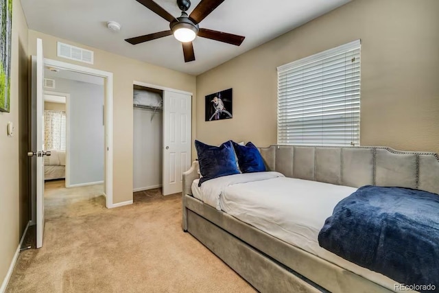 bedroom featuring light colored carpet, a closet, and ceiling fan