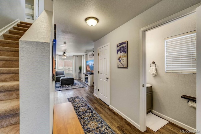 hallway with dark wood-type flooring and a textured ceiling