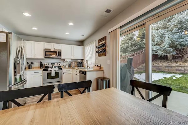 kitchen with stainless steel appliances, white cabinetry, and sink