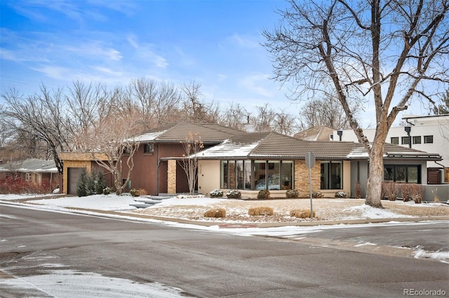 view of front of house with a garage, a tiled roof, and stucco siding