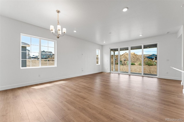 spare room with a notable chandelier and light hardwood / wood-style flooring