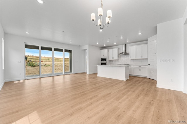 unfurnished living room featuring an inviting chandelier and light hardwood / wood-style floors