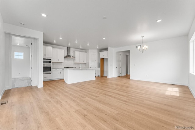 unfurnished living room with light hardwood / wood-style floors and a notable chandelier