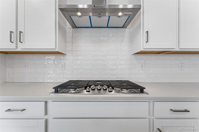 kitchen featuring white cabinets, stainless steel gas stovetop, tasteful backsplash, and range hood