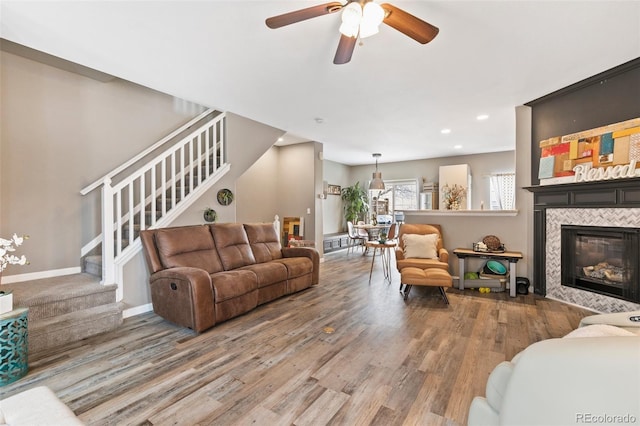 997 Burning Bush Pt, Monument, CO 80132 - living area featuring stairs, wood finished floors, a ceiling fan, a tile fireplace, and recessed lighting