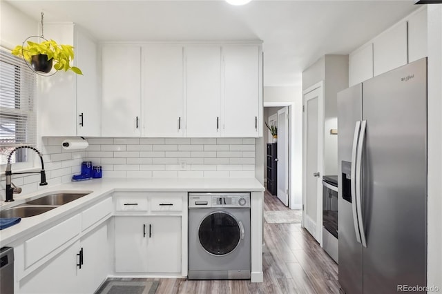 kitchen featuring sink, white cabinets, stainless steel appliances, washer / clothes dryer, and backsplash