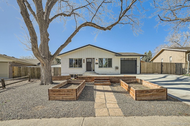bungalow featuring a garden, an attached garage, fence, and concrete driveway