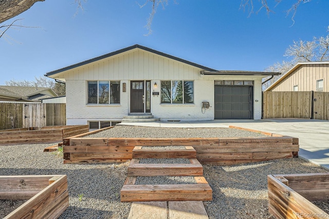 view of front of property with a garage, fence, driveway, and a vegetable garden