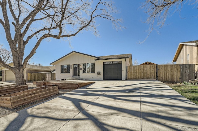 view of front of property with a garden, a garage, fence, concrete driveway, and a gate