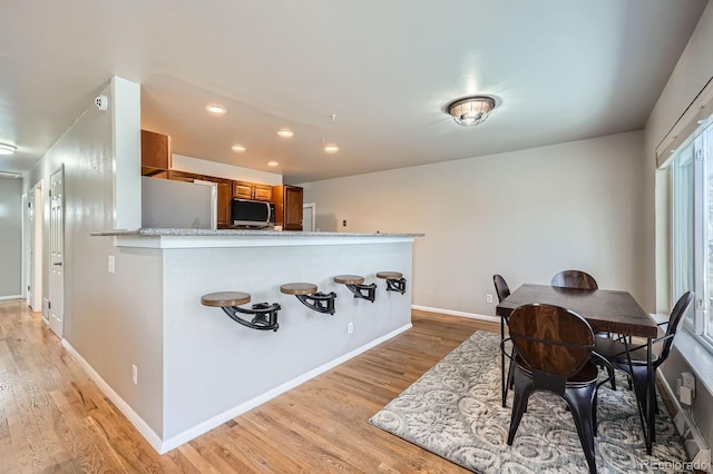 dining room featuring baseboards, light wood finished floors, and recessed lighting