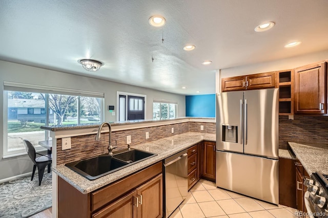 kitchen with tasteful backsplash, a sink, a peninsula, recessed lighting, and stainless steel appliances