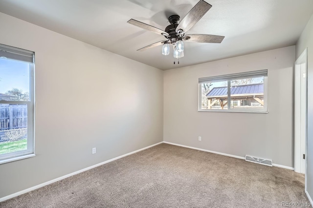 empty room with ceiling fan, baseboards, visible vents, and carpet floors