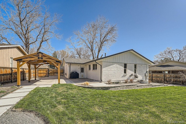 rear view of house featuring a patio area, brick siding, a fenced backyard, a gazebo, and a lawn