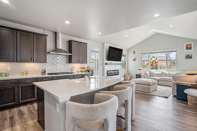 4532 Dewey Ln, Brighton, CO 80603 - kitchen featuring wall chimney range hood, a sink, open floor plan, lofted ceiling, and light wood-style flooring