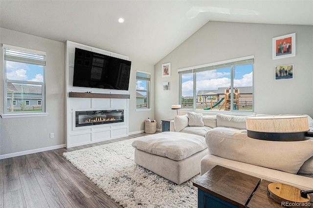 4532 Dewey Ln, Brighton, CO 80603 - living room with wood finished floors, lofted ceiling, baseboards, a glass covered fireplace, and recessed lighting