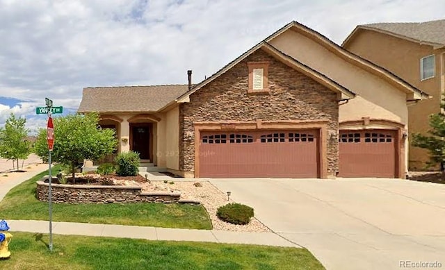 view of front of house with an attached garage, concrete driveway, stucco siding, and stone siding