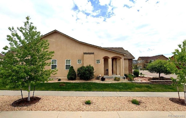 view of front of house with stucco siding and a front lawn