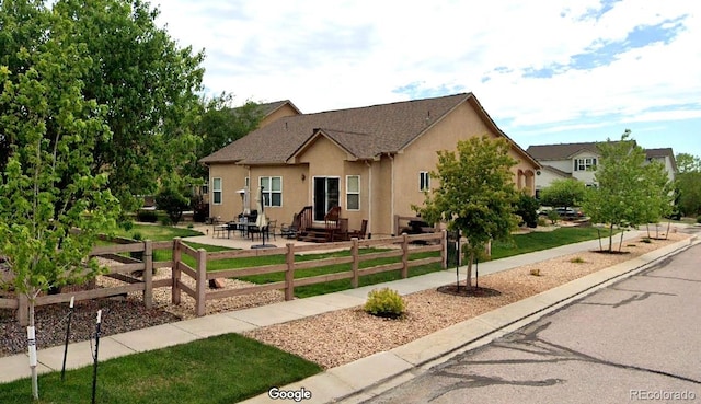 view of front facade featuring a patio area, stucco siding, fence, and a front lawn