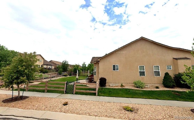 view of side of property with a yard, stucco siding, and fence