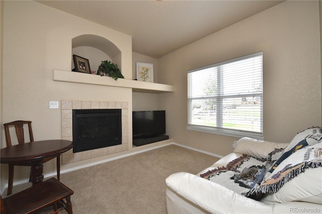 living room with carpet, a tile fireplace, baseboards, and vaulted ceiling