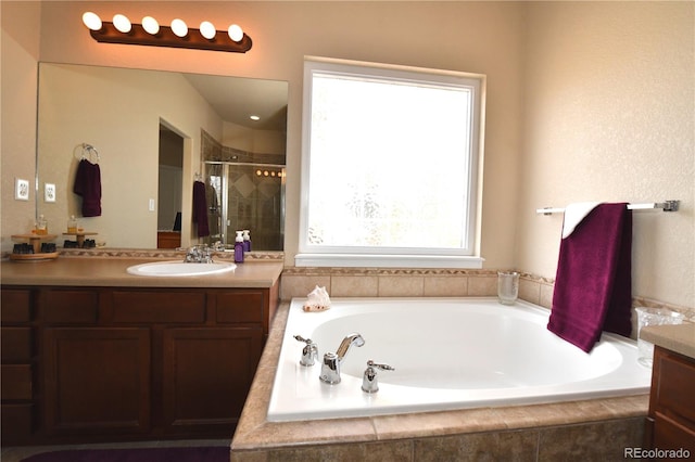 bathroom featuring a stall shower, a garden tub, and vanity
