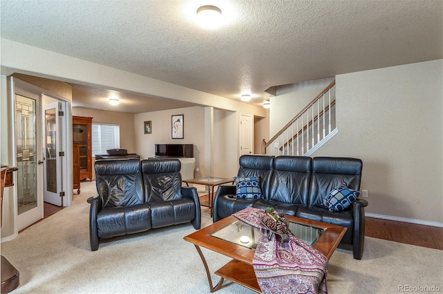 carpeted living area with stairway, baseboards, and a textured ceiling