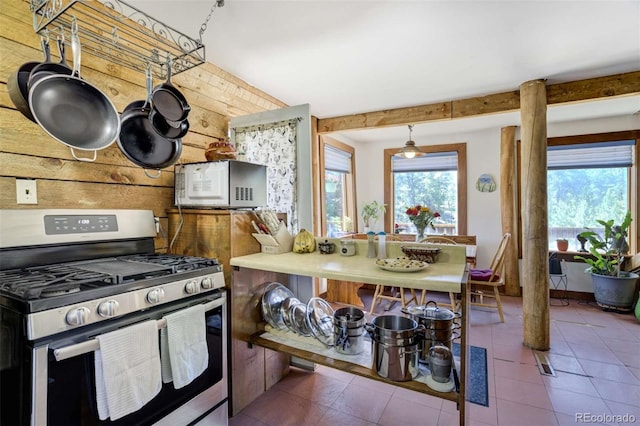 351 Badger Cir, Guffey, CO 80820 - kitchen featuring stainless steel gas range, white microwave, wooden walls, and tile patterned floors