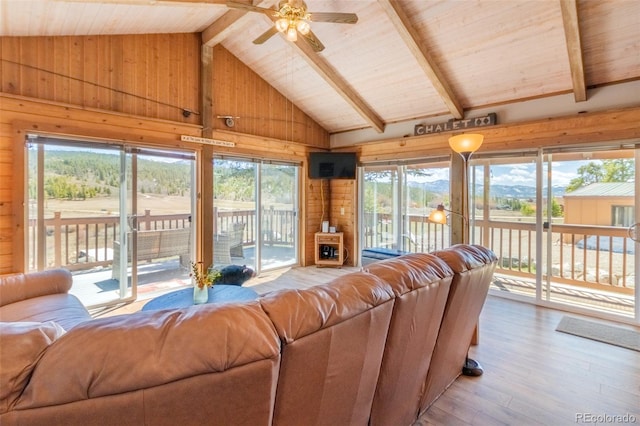1348 Gcr 64, Grand Lake, CO 80447 - living area featuring wooden walls, wood-type flooring, plenty of natural light, beam ceiling, and a ceiling fan