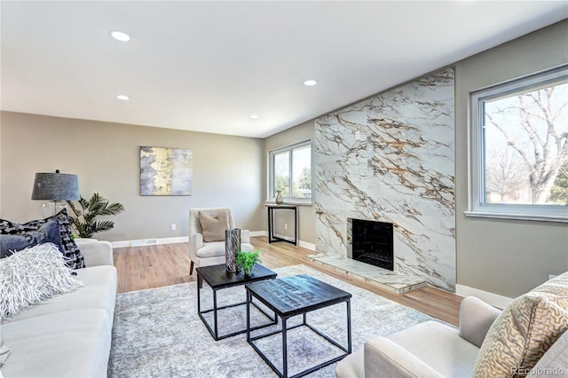 living area featuring light wood finished floors, visible vents, baseboards, a premium fireplace, and recessed lighting