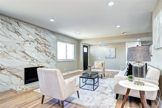 living room with baseboards, visible vents, a premium fireplace, recessed lighting, and light wood-type flooring