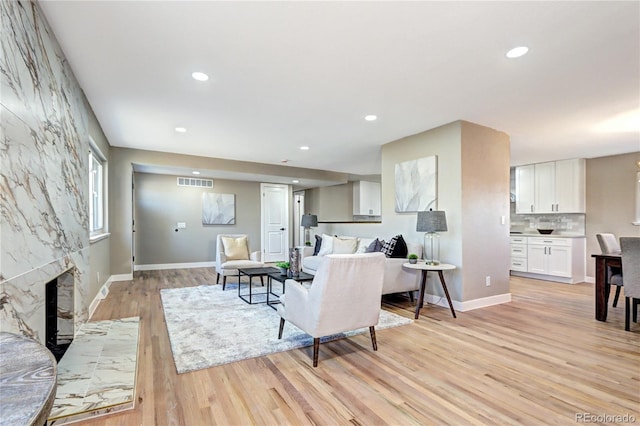 living room with visible vents, recessed lighting, light wood-style floors, a fireplace, and baseboards