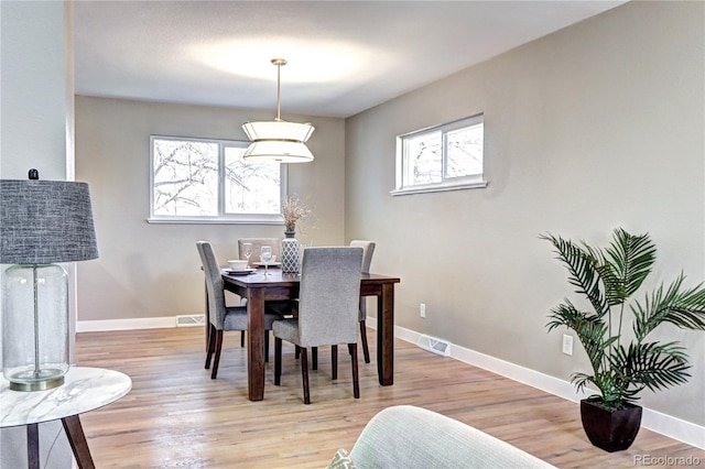 dining area featuring light wood-type flooring, visible vents, and baseboards