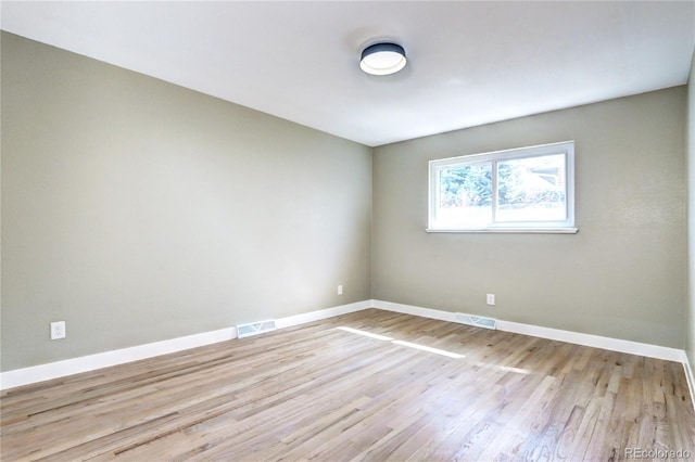 spare room featuring visible vents, baseboards, and wood finished floors