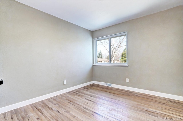 spare room with visible vents, baseboards, and light wood finished floors