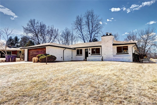 view of front facade featuring driveway, a chimney, a garage, and a front yard