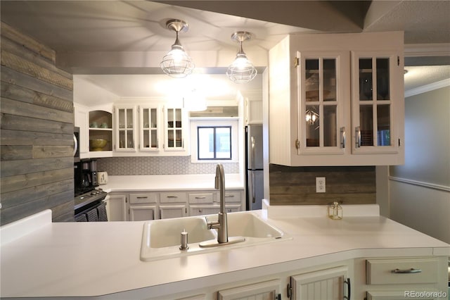 kitchen with a sink, white cabinets, light countertops, appliances with stainless steel finishes, and glass insert cabinets