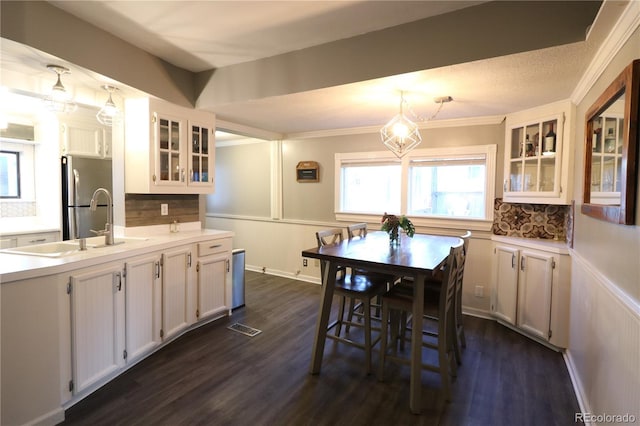 kitchen featuring dark wood-type flooring, visible vents, white cabinets, freestanding refrigerator, and decorative backsplash