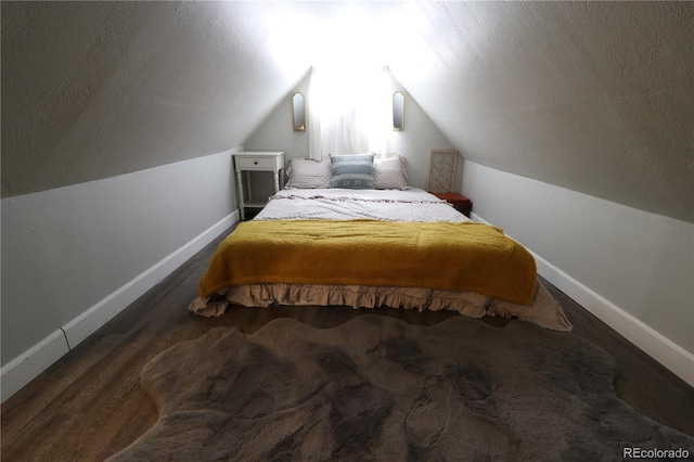 bedroom featuring baseboards, vaulted ceiling, and a textured ceiling