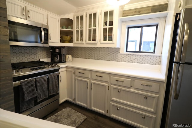 kitchen with light countertops, appliances with stainless steel finishes, decorative backsplash, open shelves, and glass insert cabinets