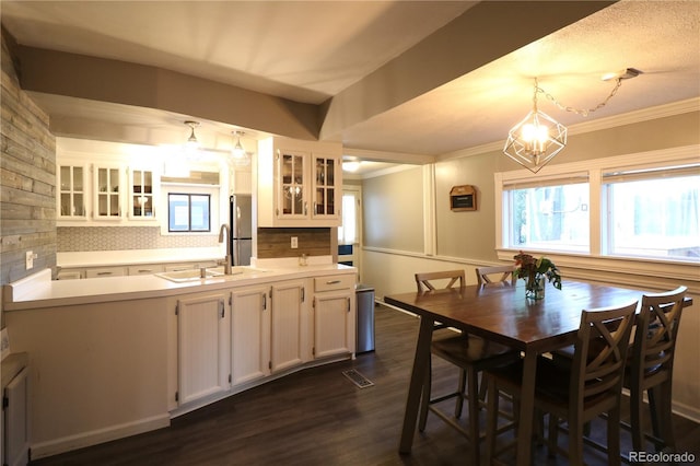 kitchen featuring a sink, white cabinetry, freestanding refrigerator, dark wood-style floors, and decorative light fixtures