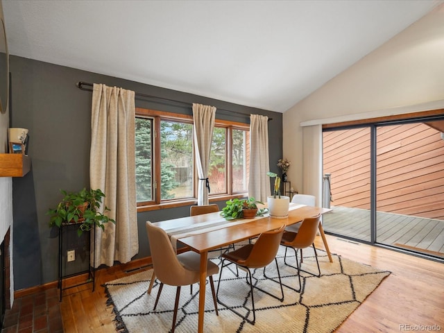 dining space with lofted ceiling, baseboards, and wood finished floors