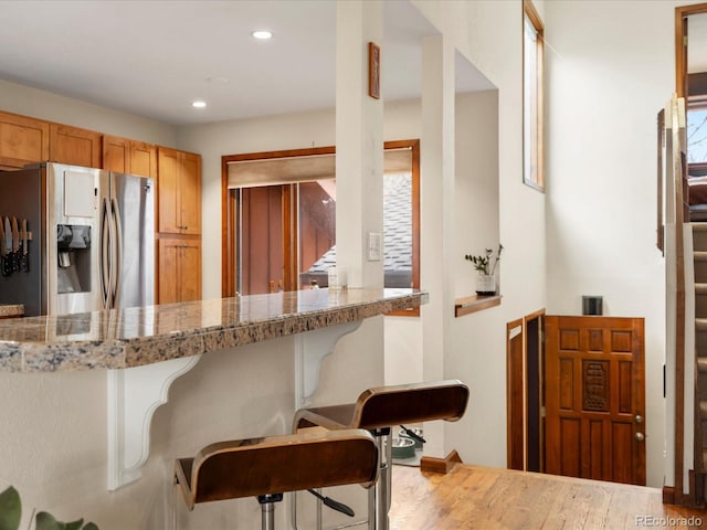 kitchen with recessed lighting, a kitchen bar, wood finished floors, and stainless steel fridge with ice dispenser