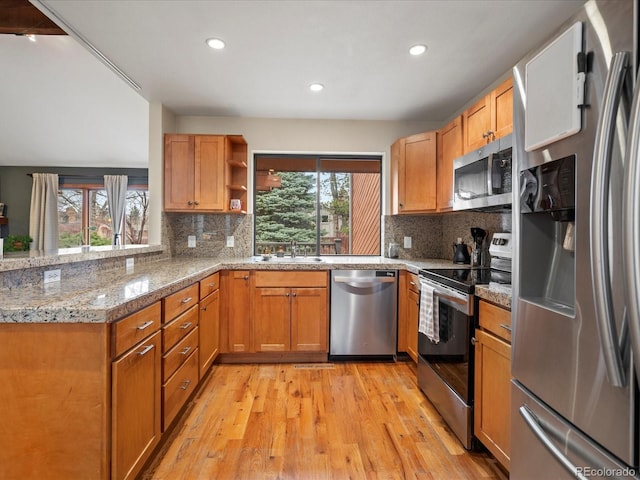 kitchen with light wood-style flooring, appliances with stainless steel finishes, a healthy amount of sunlight, open shelves, and a sink