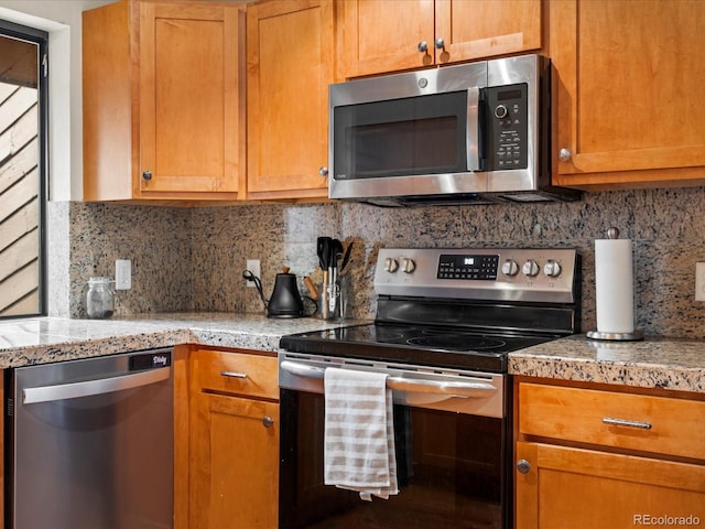 kitchen with stainless steel appliances, tasteful backsplash, brown cabinetry, and light countertops