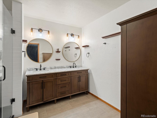 full bath with a stall shower, a sink, baseboards, and double vanity