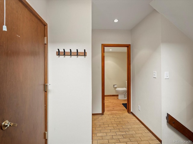 hallway with recessed lighting, brick floor, and baseboards