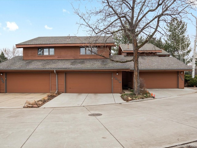 view of front of property featuring an attached garage, a shingled roof, and concrete driveway