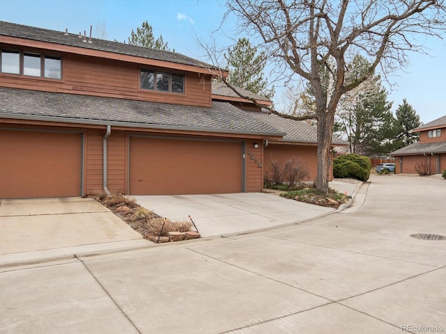 view of front facade featuring driveway, a shingled roof, and an attached garage